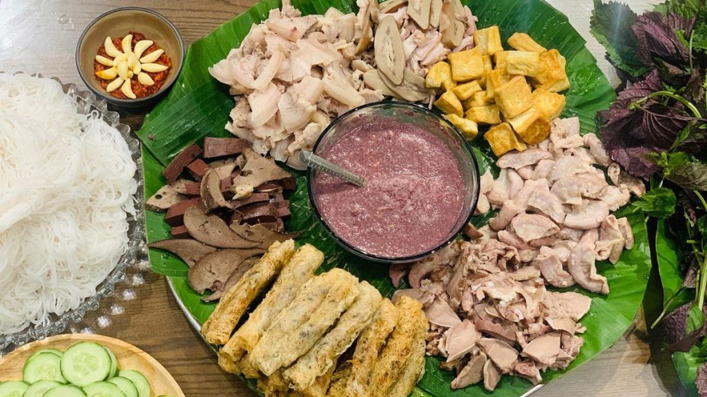 Mẹt bún đậu mắm tôm chuẩn vị Hà Nội với đầy đủ thành phần gồm bún lá trắng tinh, đậu phụ chiên vàng giòn, thịt luộc, lòng, dồi, chả cốm, rau thơm và chén mắm tôm dậy mùi, bày biện trên mẹt tre lót lá chuối.