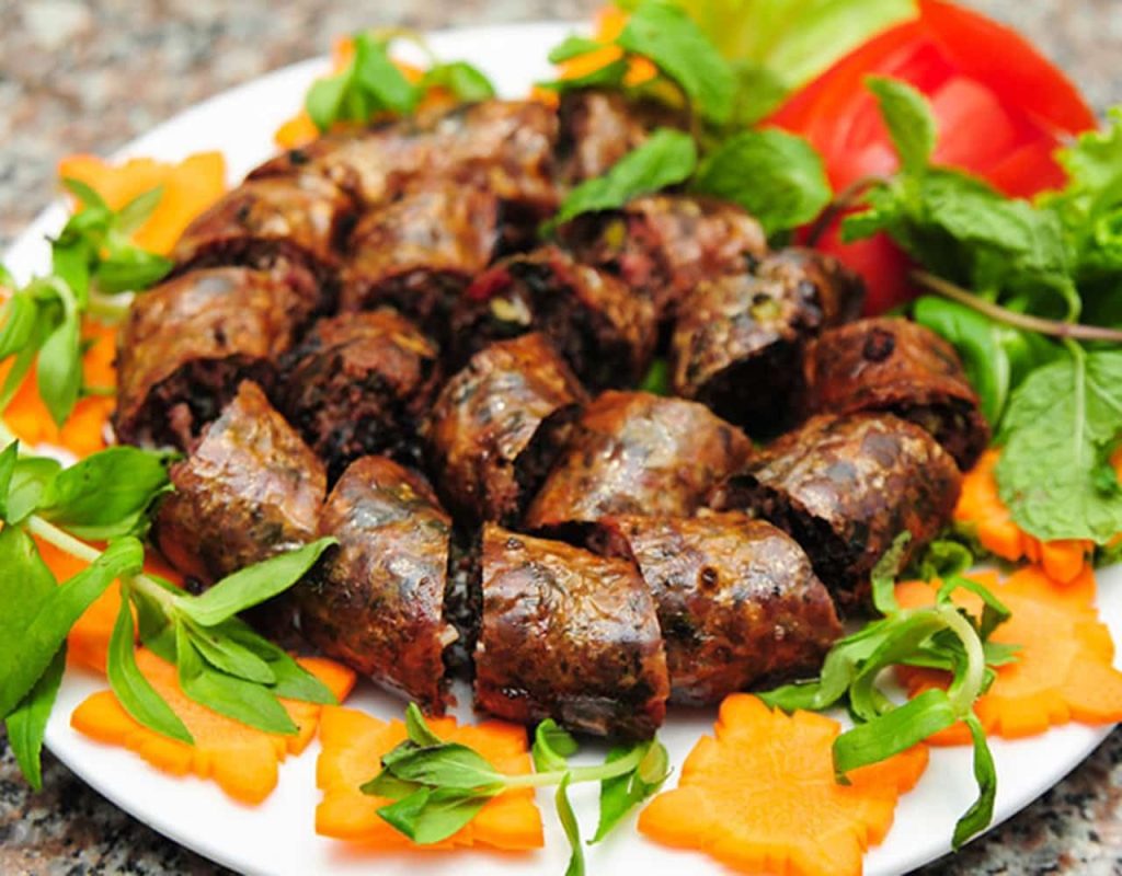 Dồi sụn chiên cắt khoanh bày trên đĩa, trang trí rau thơm và cà rốt tỉa hoa đẹp mắt.