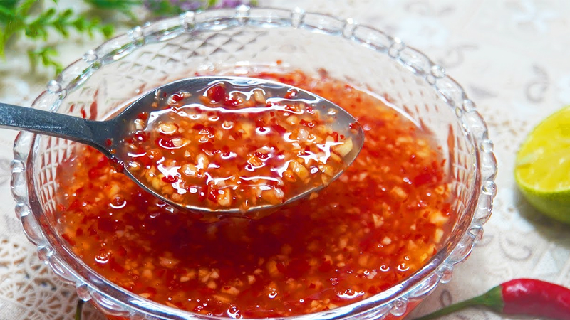 Chén nước mắm bún chả đậm vị với tỏi và ớt băm được đựng trong tô thủy tinh.
